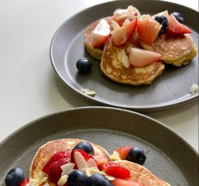 Stack of delicious pancakes topped with fresh berries and sliced almonds.