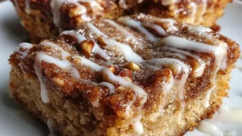 Cinnamon Roll Bliss Bars topped with creamy icing on a rustic wooden table