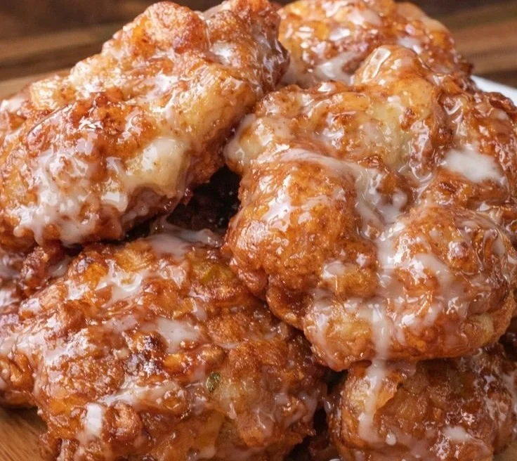 Delicious baked apple fritters on a platter with a dusting of powdered sugar