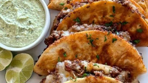 Crispy ground beef tacos topped with fresh ingredients and served on a plate