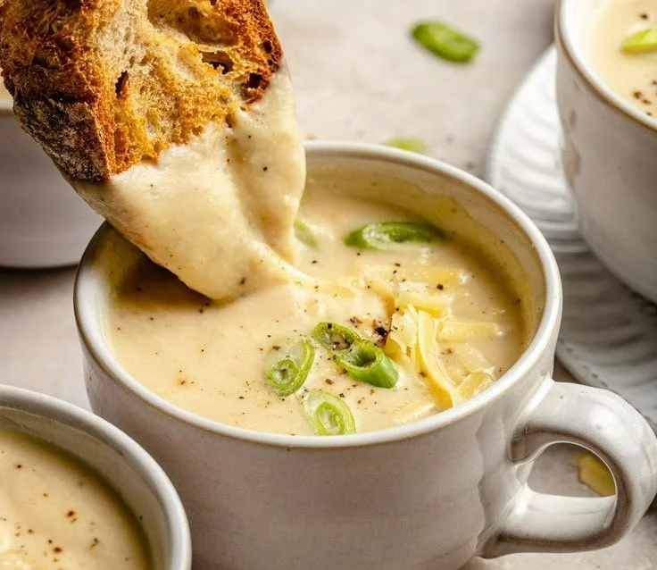 Bowl of creamy roasted cauliflower soup garnished with herbs