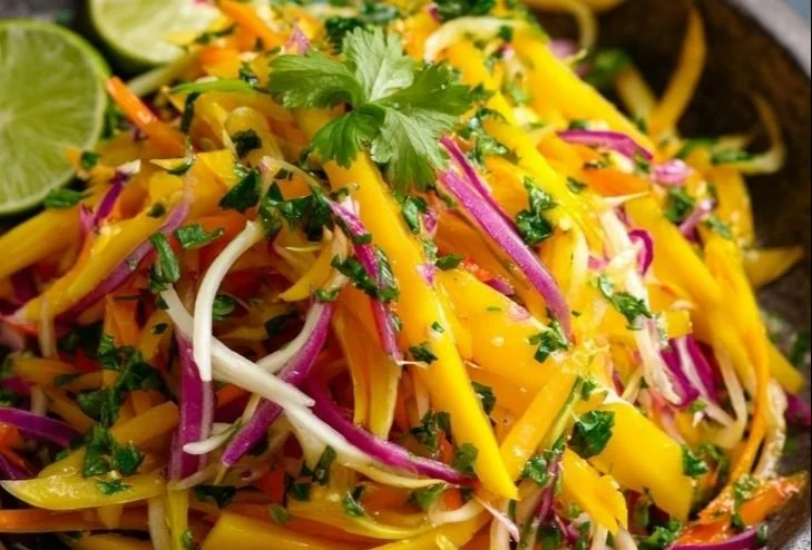 Colorful mango slaw with cabbage, carrots, and dressing in a bowl