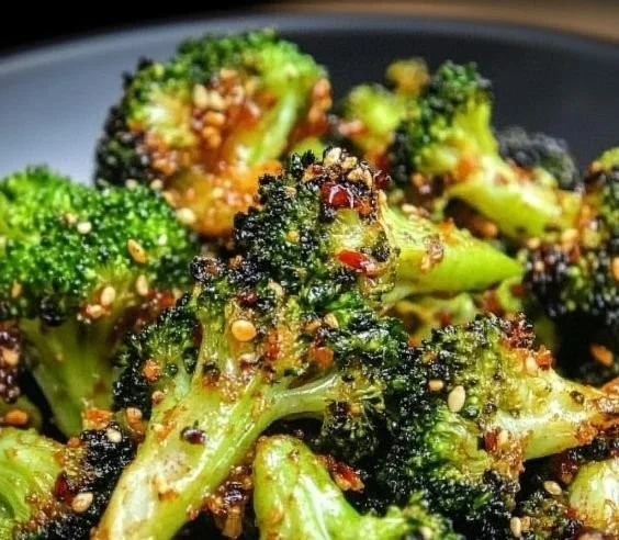 Sweet chili roasted broccoli garnished with sesame seeds in a serving bowl.
