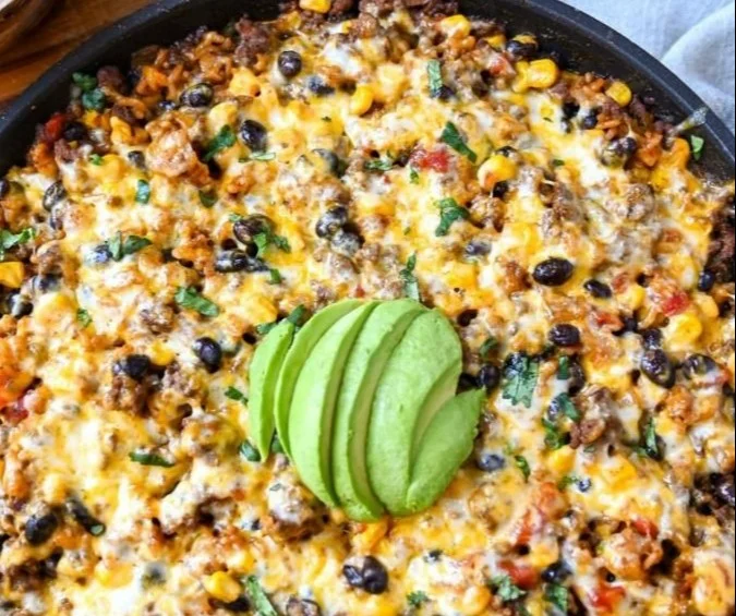 Cheesy taco rice skillet topped with melted cheese and fresh toppings