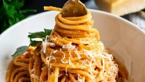 A bowl of creamy tomato pasta topped with fresh basil and Parmesan cheese