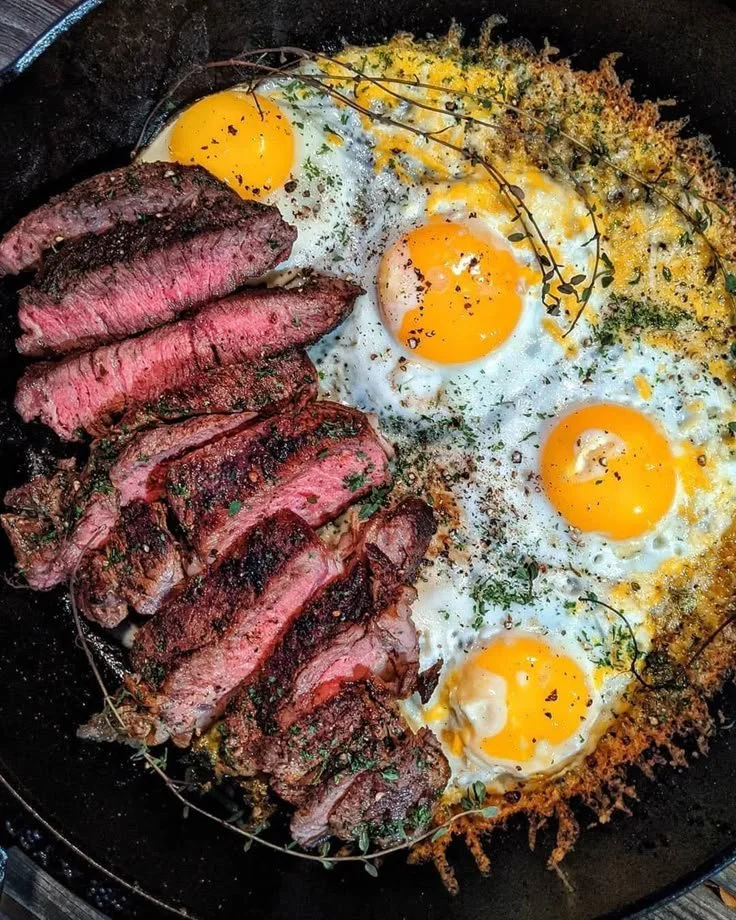 A delicious plate of steak and eggs served with herbs and spices for breakfast.