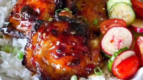 Sticky sweet chili chicken thighs cooked in an air fryer, garnished with herbs.