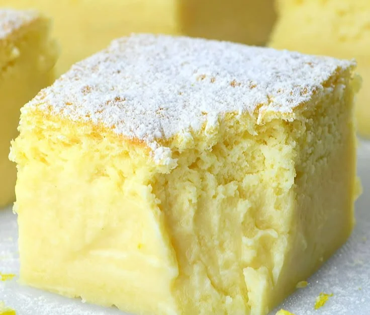 Sliced Magic Lemon Custard Cake with fresh lemon slices on top